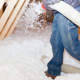 Person blowing in cellulose insulation into home attic
