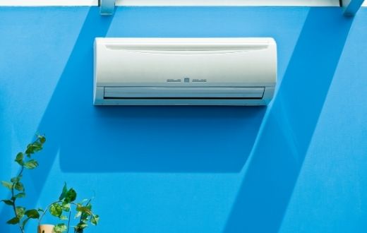 Ductless heat pump head on a bright blue wall