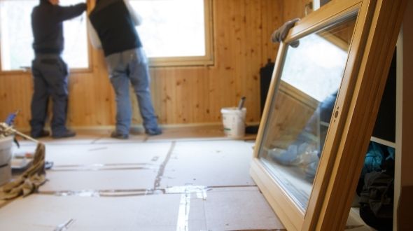 Two people installing new windows in home in background with new window in foreground
