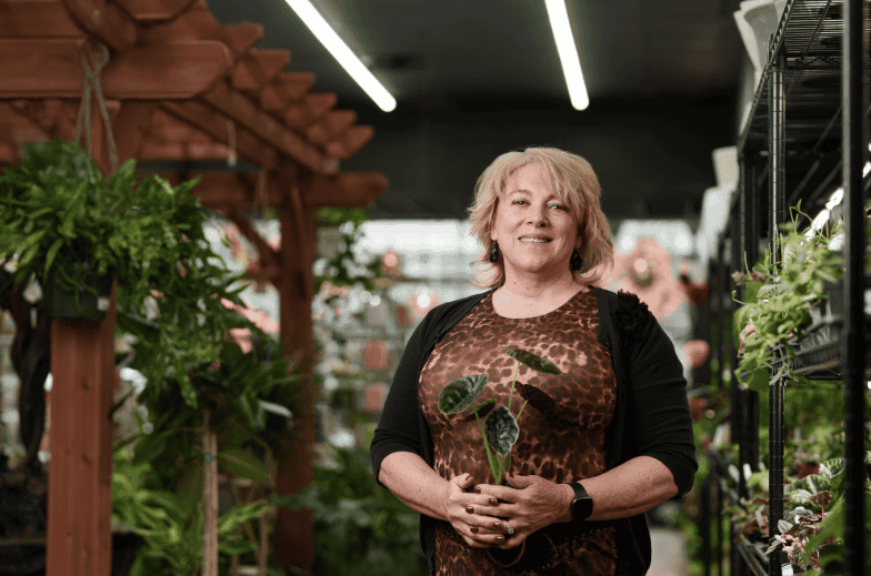 A woman stands in her business with new lighting in the background