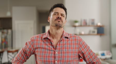 a man stands with his hands on his hips while looking at something in his home