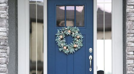 a blue front door with a wreath hanging on it