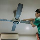 Person on ladder cleaning ceiling fan and changing rotation direction