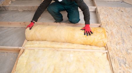 a person unrolls an insulation batting in the floor