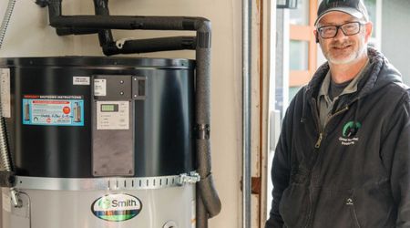 a technician stands next to an installed heat pump water heater