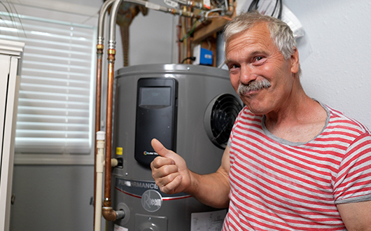 Mr. No One Ever stands next to his hybrid water heater and gives thumbs up