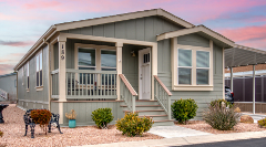 a light green manufactured home on a lot with sunset in the background
