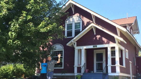 Mark and Thea wave in front of their energy efficient historic home