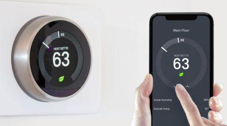 a person uses their phone to change the temperature on their smart thermostat
