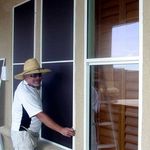 Man showing solar screen mounted outside house window