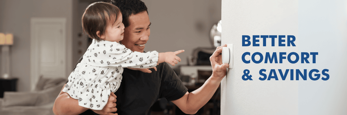 a man holds his baby daughter while adjusting a smart thermostat with words 