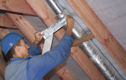 person wrapping ductwork with insulation