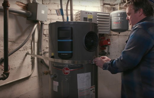 man installing new heat pump water heater in basement