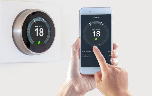 smart thermostat and person holding connected smart phone with app