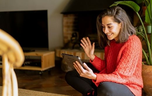 woman on tablet in home waving