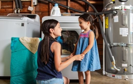 two young girls in front of clothes washer and hybrid water heater