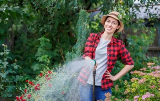 woman holding water hose in garden