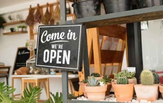 We're open sign in front of small retail shop