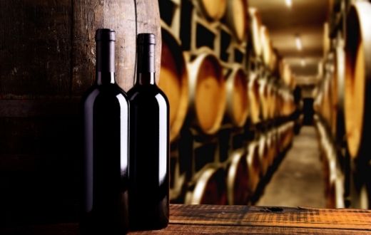 Bottles of wine on counter in front of wine barrel storage