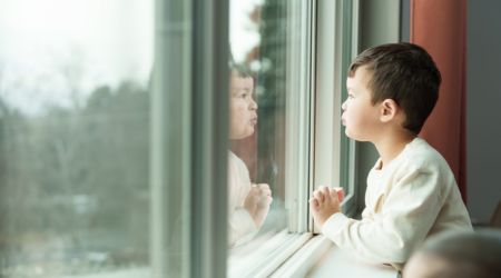 a young boy looks out a window